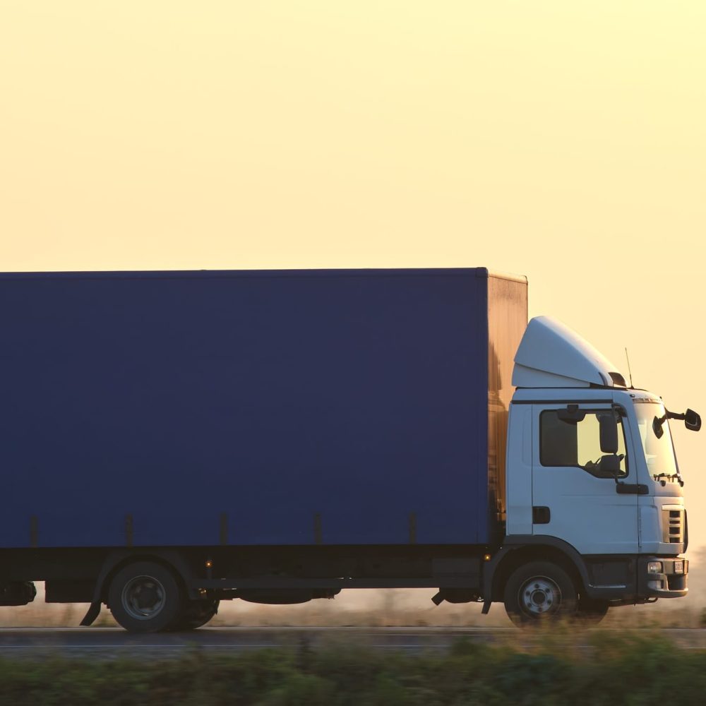 Cargo truck driving on highway hauling goods in evening. Delivery transportation and logistics