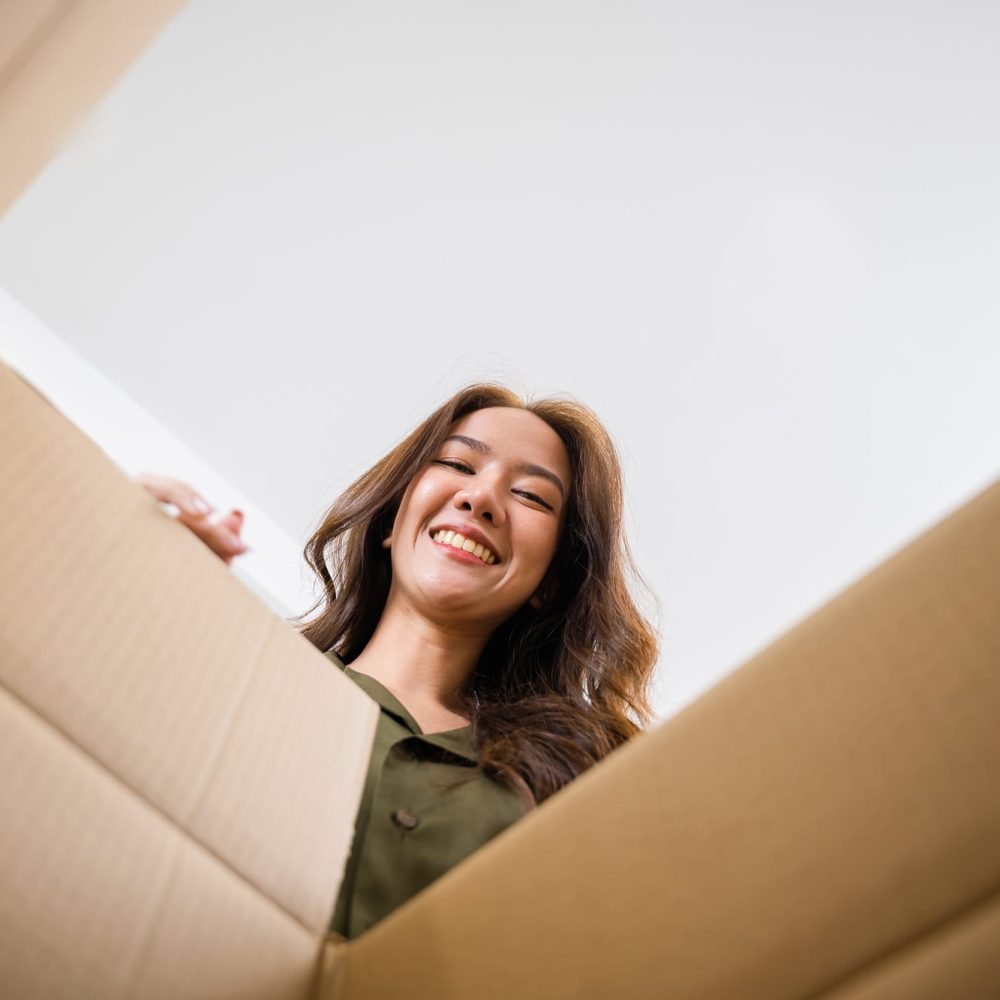 Happy Asian young woman opening carton box from internet store order shopping online